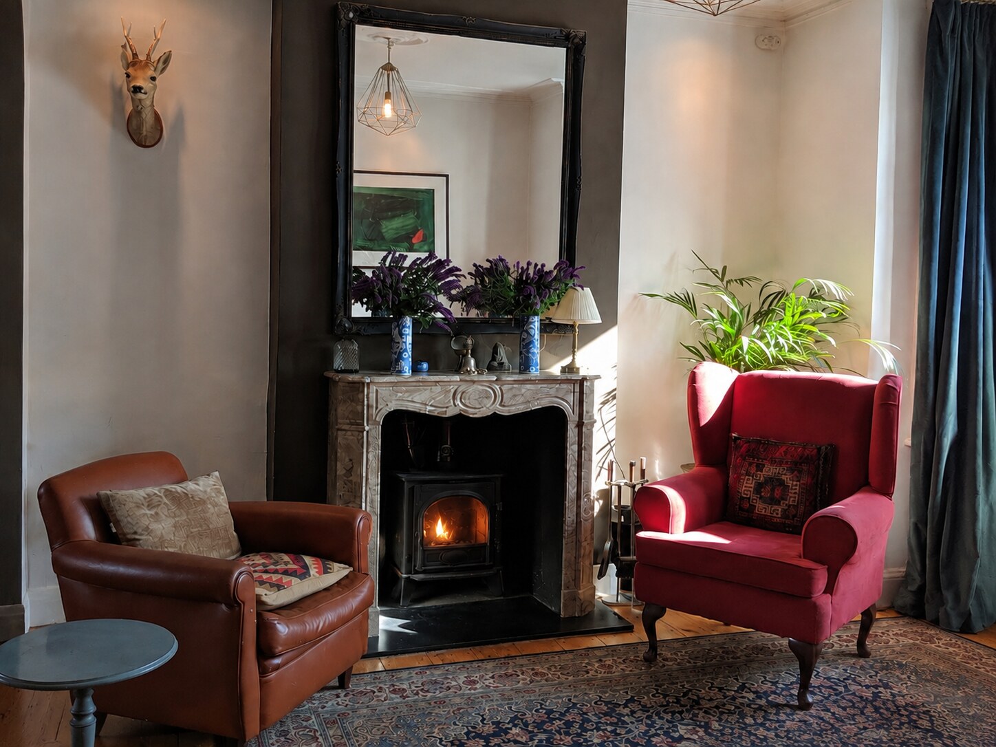 Magnus's warm therapy room in South London, with two armchairs and a lit wood burner